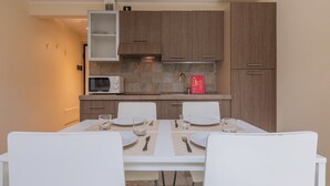 A modern kitchen with wooden cabinets, a microwave, and a dining table set for two. - Loft Cioccolato by Wonderful Italy (Turin)