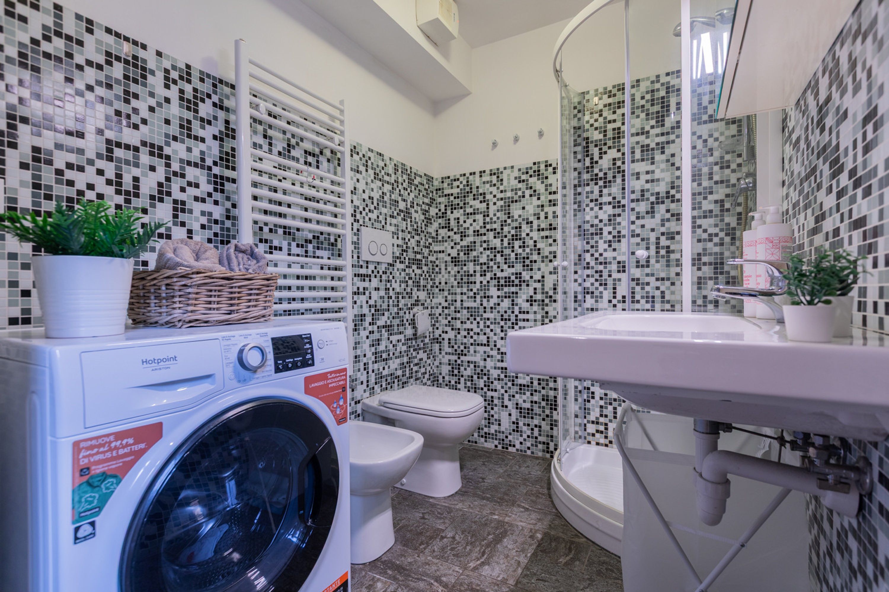 A compact bathroom with a washing machine, toilet, and sink.