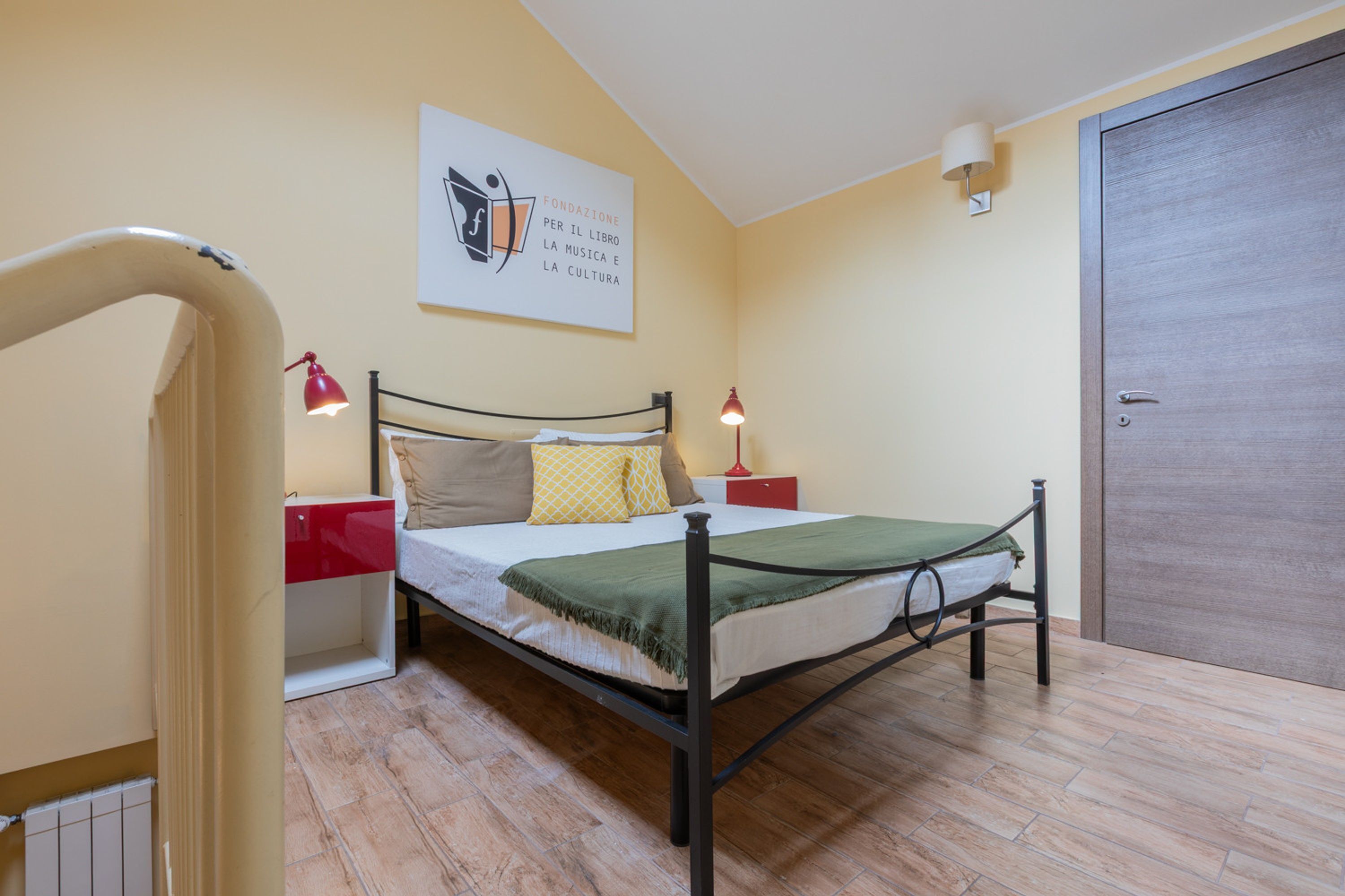 A bedroom with a bed, bedside tables, a lamp, and a door.