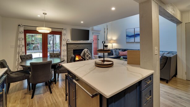 A modern kitchen with a central island, dining area with chairs, and a fireplace. - Fall Foliage, Hiking Trails, Close to Jim Thorpe! (Lake Harmony)