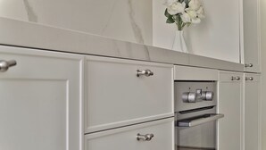 A kitchen with white cabinets, a built-in oven, and a vase with white flowers on the countertop. - Elegant 2-bed apt in the Centre of Milan (Milan)