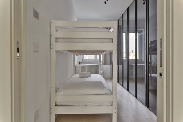 Habitación con literas y una puerta corrediza de vidrio que da a un balcón.