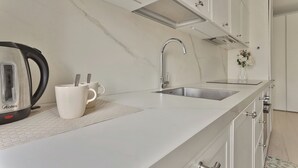 A modern kitchen with white marble countertops, stainless steel appliances, and a double sink. - Elegant 2-bed apt in the Centre of Milan (Milan)