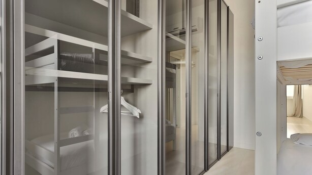 A modern hotel room with a walk-in closet featuring glass doors and built-in shelves. - Elegant 2-bed apt in the Centre of Milan (Milan)