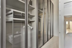 Une chambre d’hôtel moderne dotée d’un dressing avec des portes en verre et des étagères intégrées.