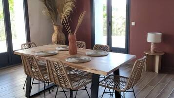 A dining area with a wooden table, wicker chairs, a vase with pampas grass, and a bull's head decoration on the wall.