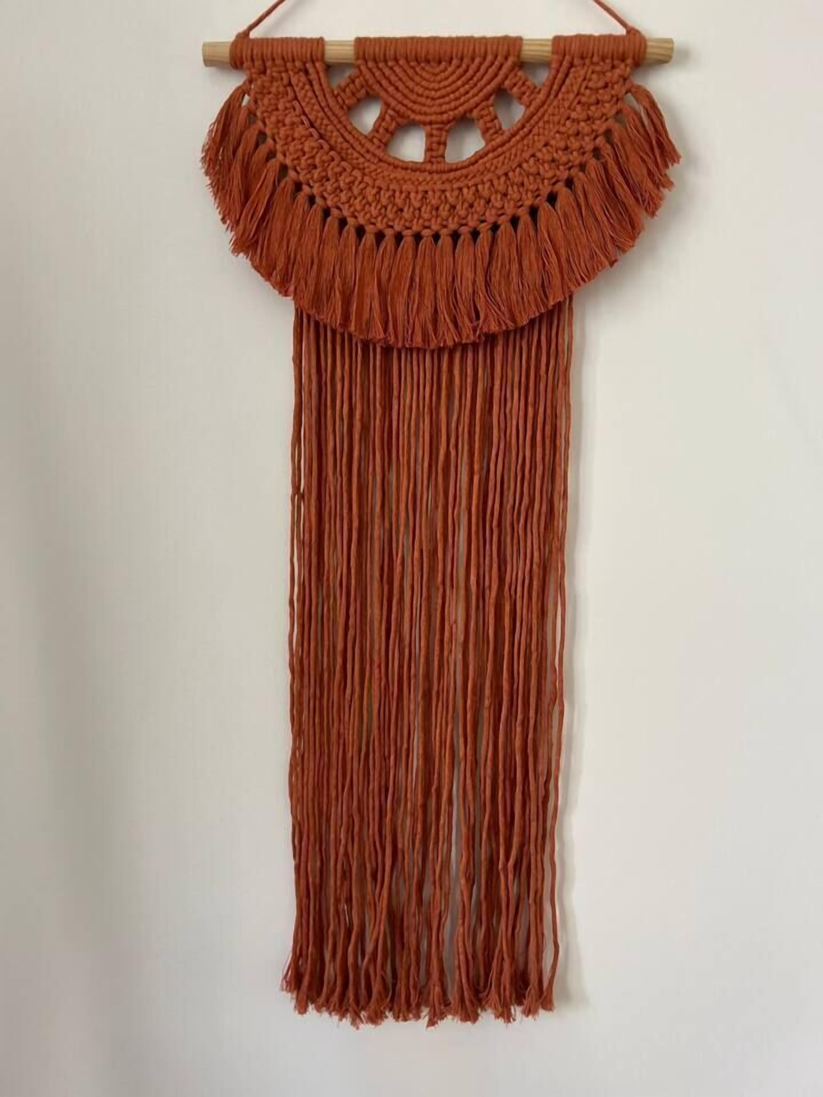 Een wanddecoratie van macramé met een houten lijst.