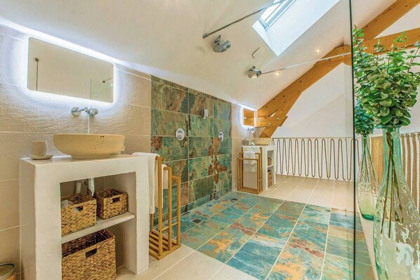 Un baño moderno con tragaluz, un espejo grande, un lavamanos independiente y una zona de ducha.