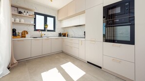 A modern kitchen with white cabinets, a black oven, and a window above the sink.