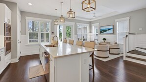 A spacious kitchen with a central island, pendant lighting, and large windows. - Surf Sanctuary + Golf Cart, Pet Friendly & Bikes (Santa Rosa Beach)