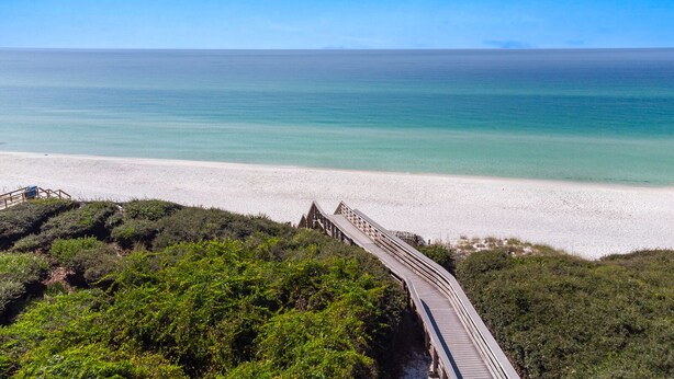 A beach with a wooden boardwalk leading to the shore, surrounded by greenery. - Surf Sanctuary + Golf Cart, Pet Friendly & Bikes (Santa Rosa Beach)