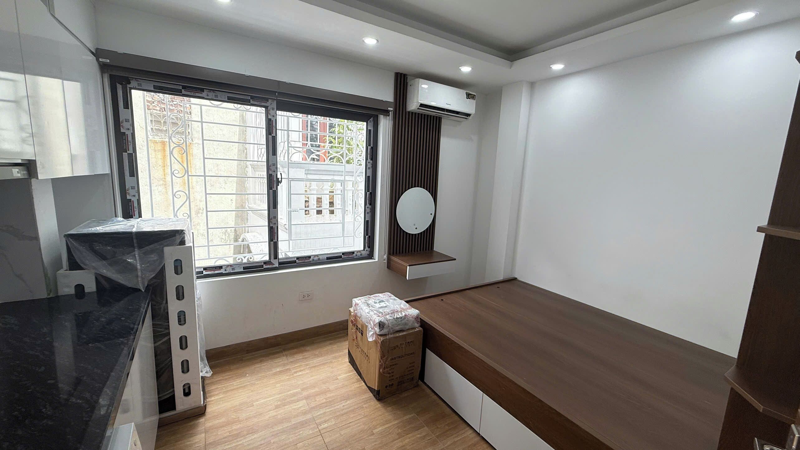 A modern kitchen with a black countertop, a window with metal bars, an air conditioning unit, and a wooden bench.