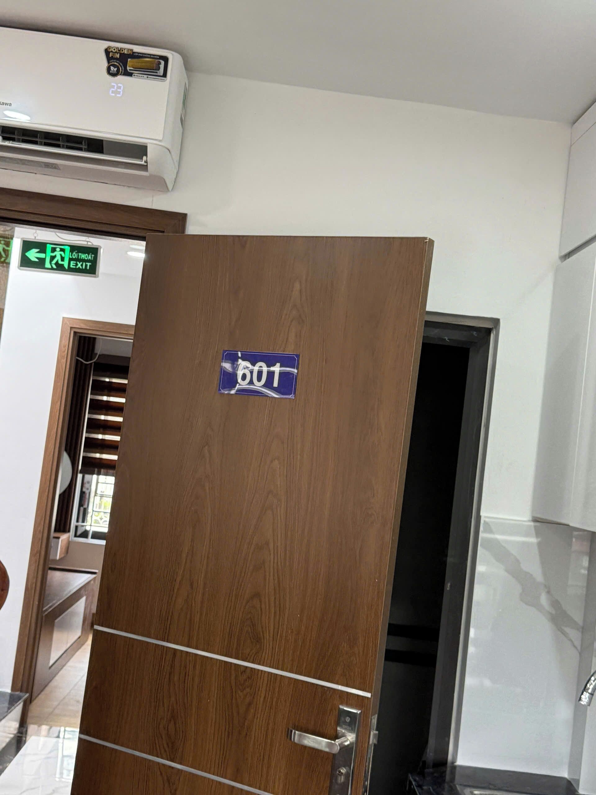 A wooden door with a sign reading "601" and an air conditioning unit above it.