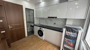 Cocina funcional con lavadora, lavamanos y puerta de madera.