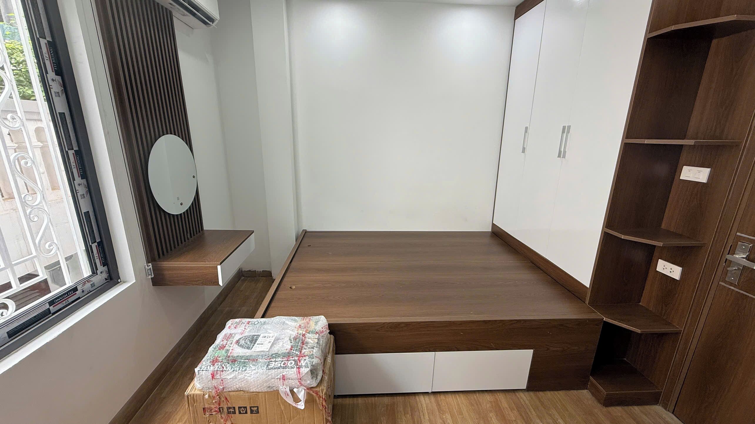 Een kamer met houten vloer, een inbouwkleerkast, een klein tafeltje en een raam met een metalen traliewerk.
