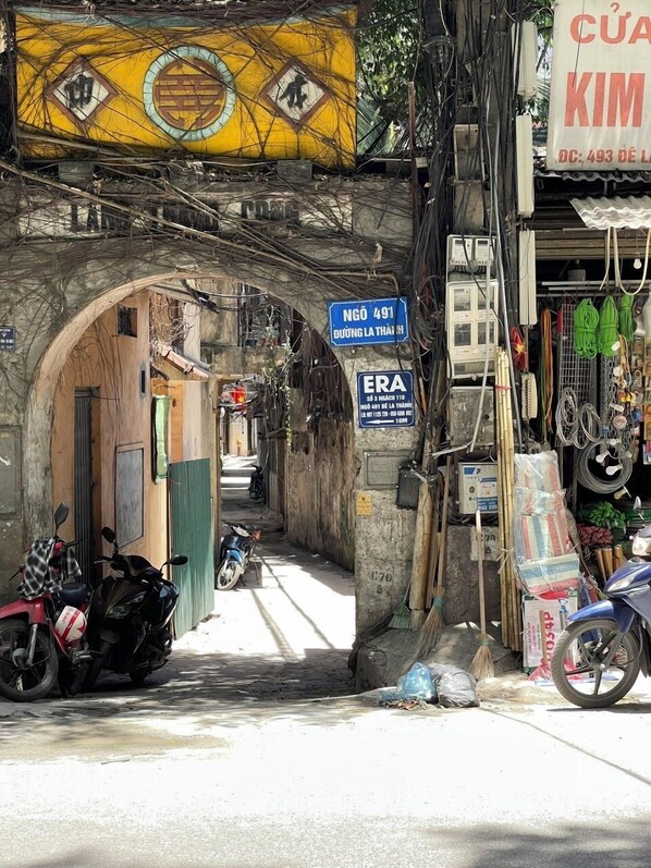 A narrow alley with a sign indicating a business named "KIM" and a sign for "NGÓ 491". - Era Apartment 491 De La Thanh (Hanoi)