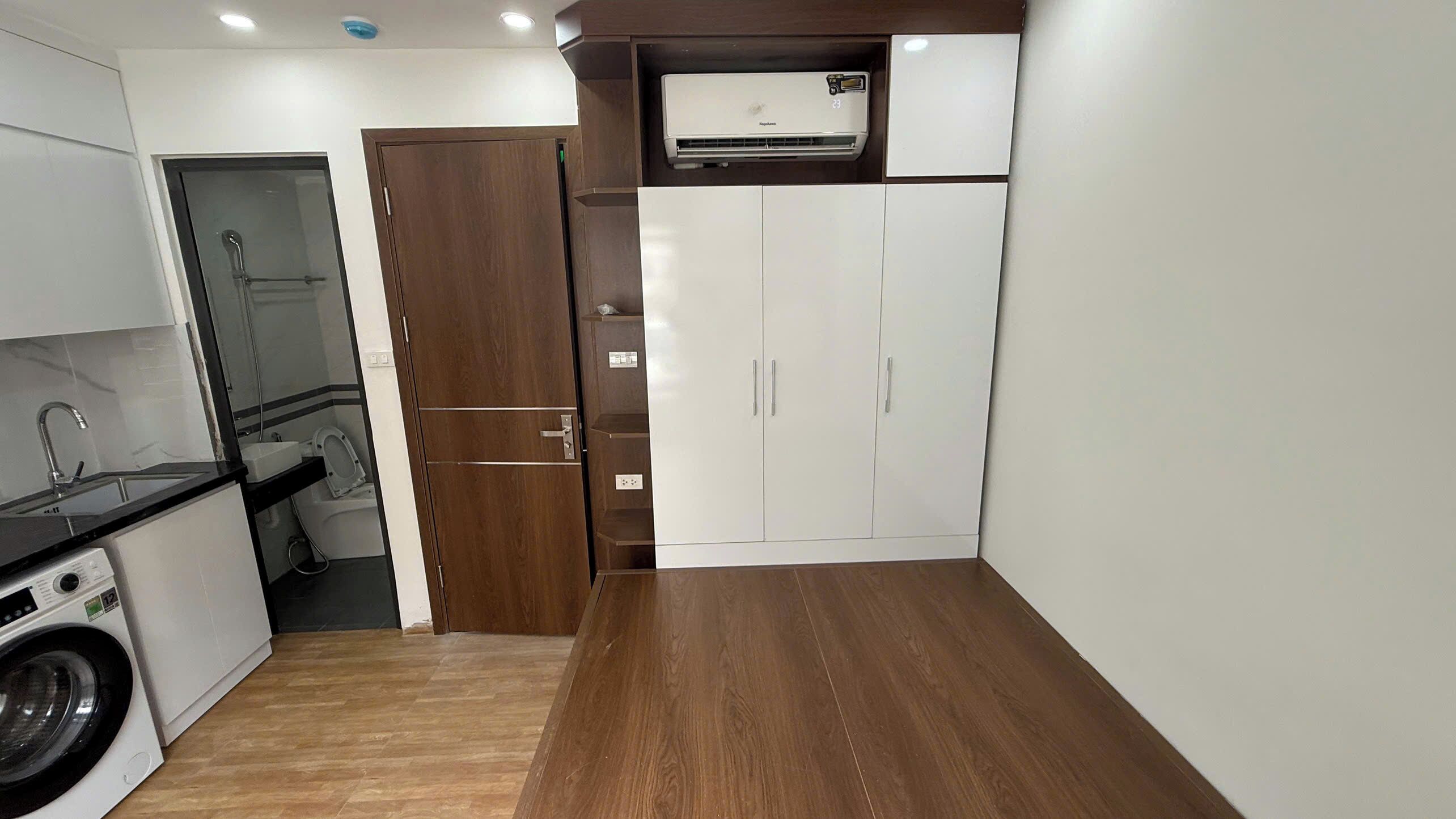 Una cocina compacta con lavadora, microondas integrado y puerta de madera.