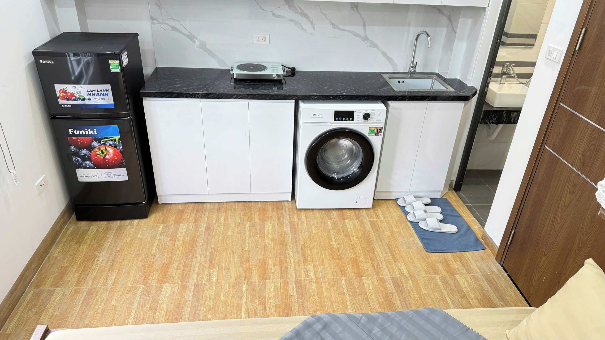 A compact kitchen with a washing machine, a refrigerator, and a sink.