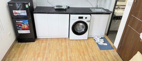A compact kitchen with a washing machine, a refrigerator, and a sink.