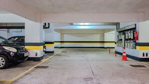 A parking garage with two cars parked, yellow and black striped walls, and a fire extinguisher mounted on the wall. - Apto pet Friendly c Garagem em Rio Vermelho (Salvador)