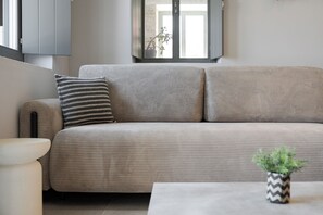 Un salon moderne avec un canapé, une petite table d’appoint et une plante en pot.