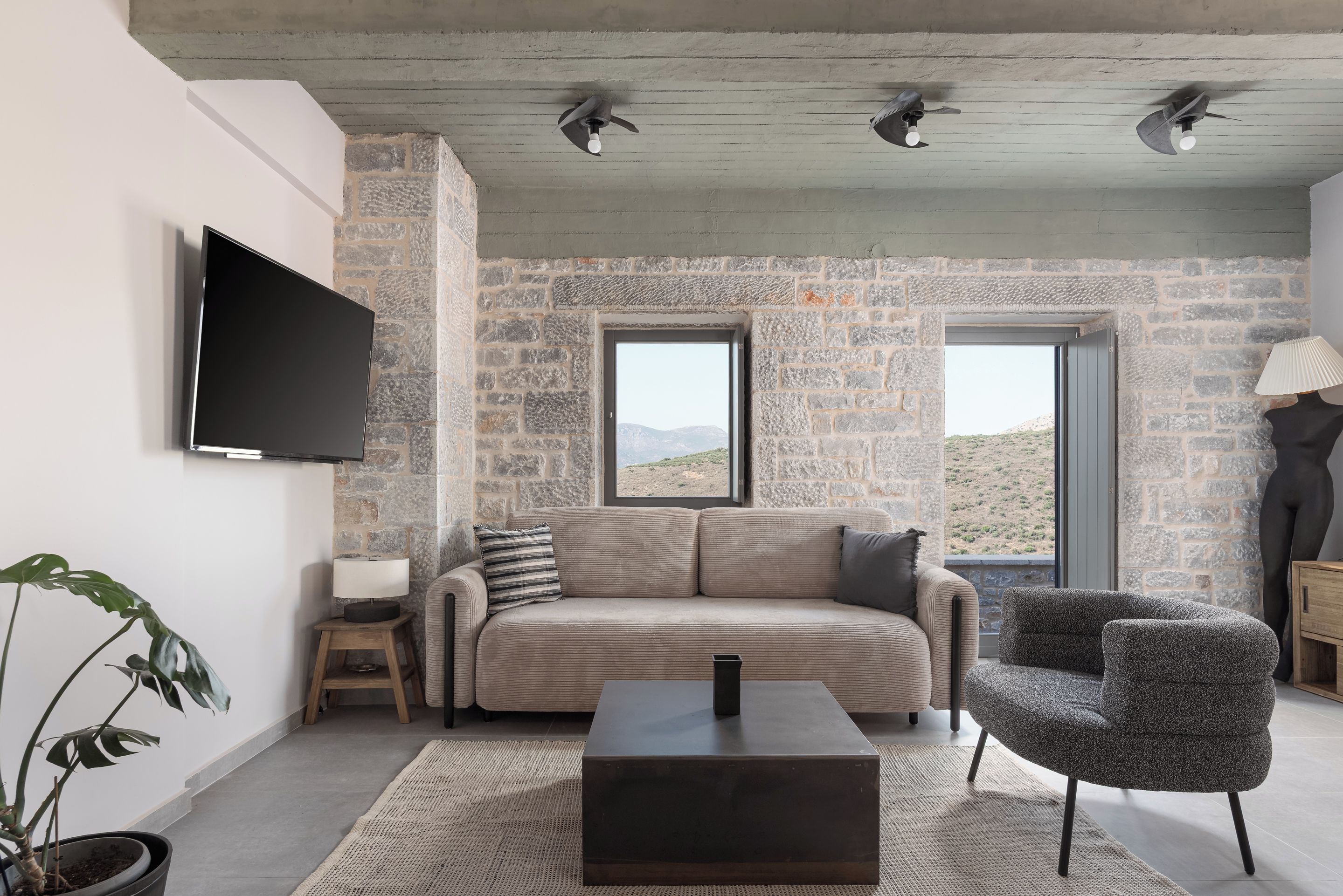 Un soggiorno moderno con una parete in pietra, un divano, un tavolino e una TV a parete.