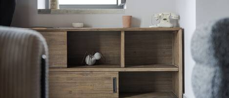 Ein modernes Wohnzimmer mit einem Holzschrank, einer kleinen Topfpflanze und einem Vintage-Telefon.