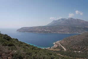 Un paysage côtier offrant une vue dégagée sur la mer, une route sinueuse et un petit village avec quelques bâtiments.