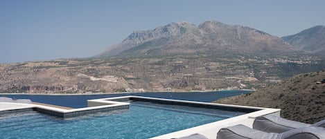 An infinity pool with a view of mountains and a body of water.