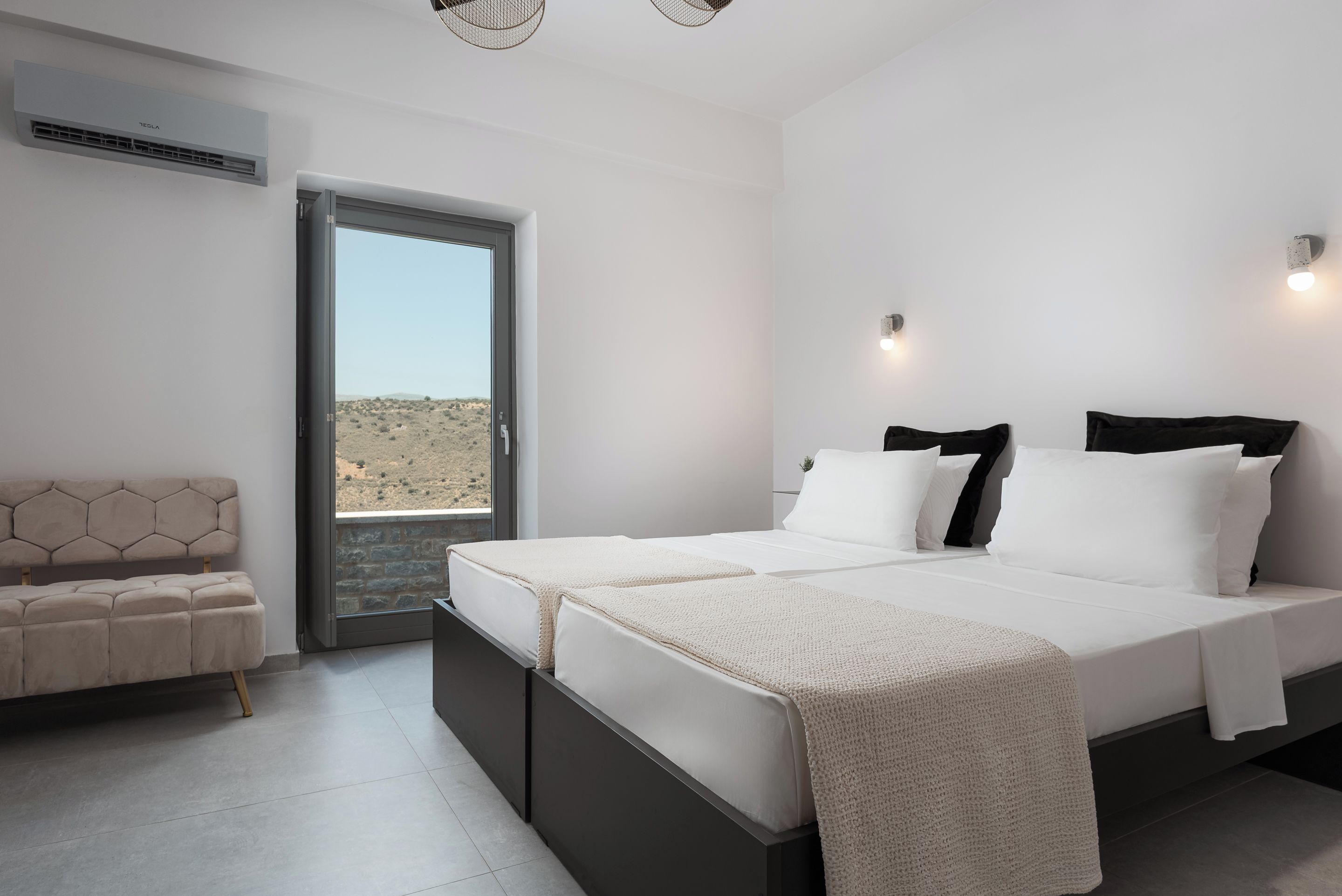 Un dormitorio moderno con una cama grande, un sofá y vistas a un paisaje desértico a través de un ventanal.