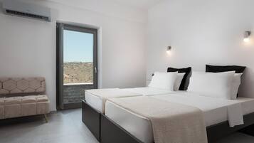 Un dormitorio moderno con una cama grande, un sofá y vistas a un paisaje desértico a través de un ventanal.