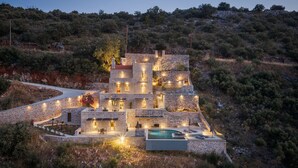 Una villa de piedra con varias habitaciones, piscina y una entrada sinuosa.