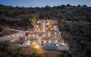 Une villa en pierre dotée de nombreuses chambres, d’une piscine et d’une allée sinueuse.