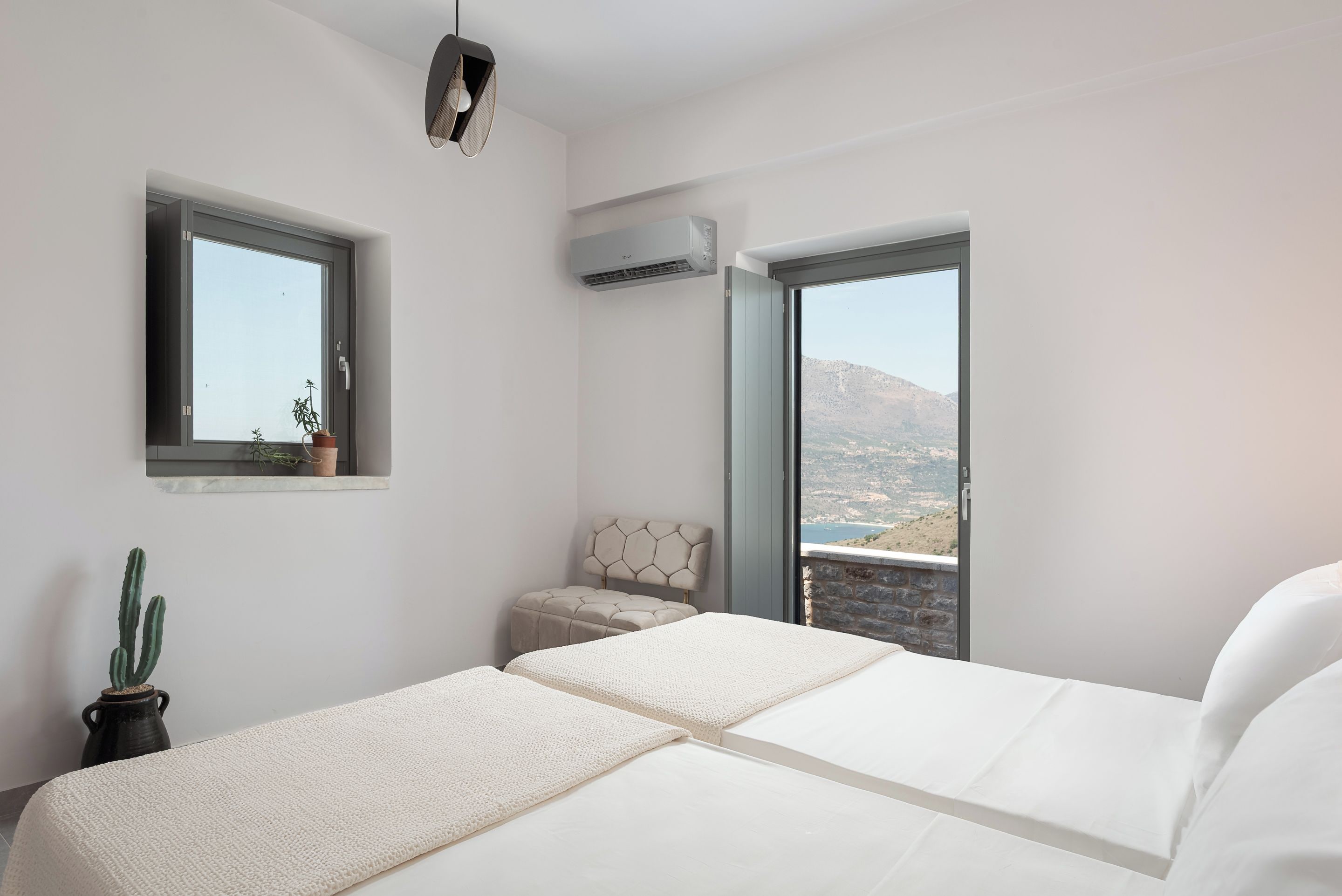 Un dormitorio con una cama, un ventanal, una planta en maceta y vistas al paisaje.