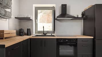 A modern kitchen with black cabinetry, a built-in oven, and a window with a view of the outdoors.