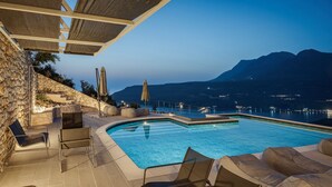 Una piscina con sillones de descanso y vistas a las montañas.