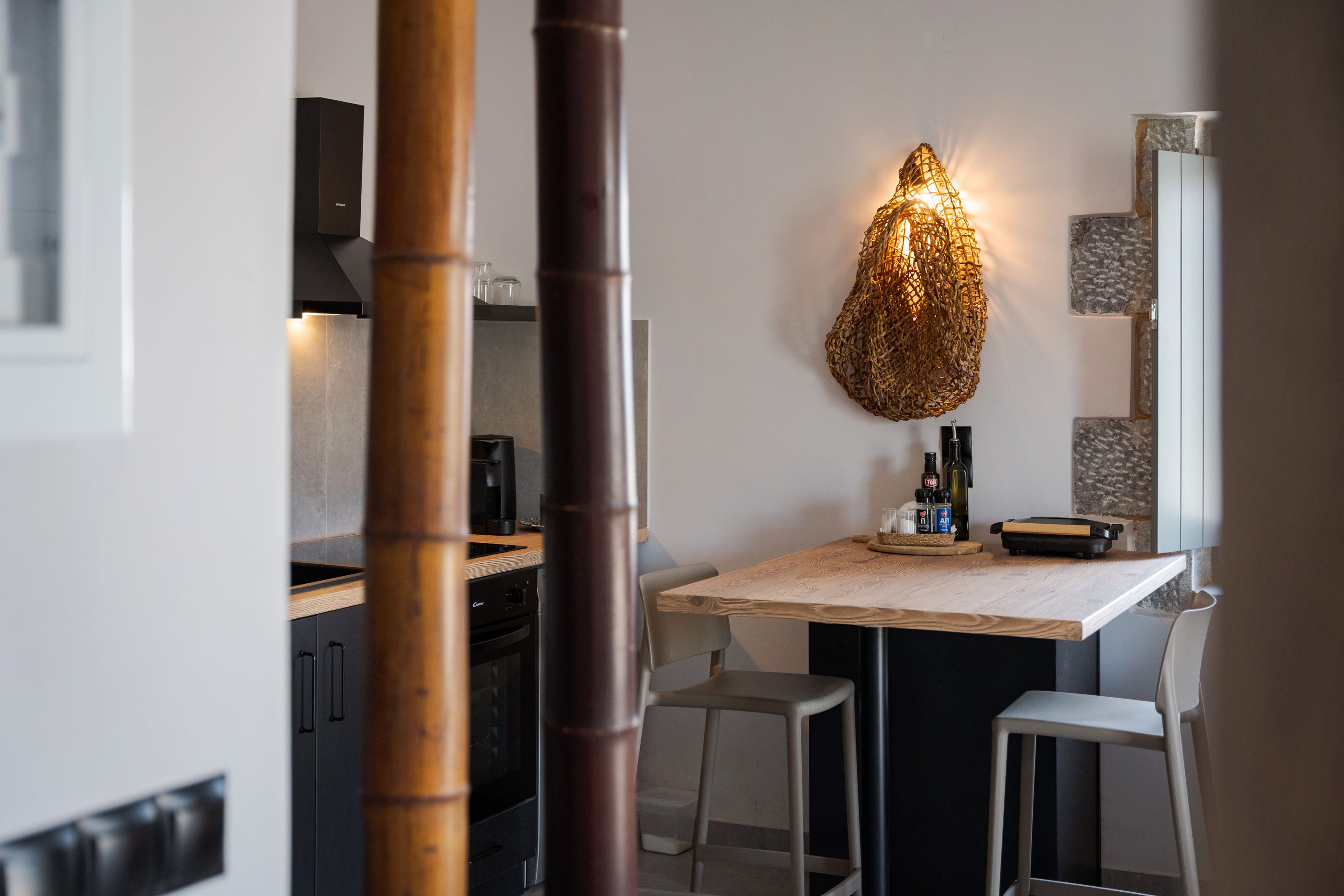 A modern kitchen with a dining table, chairs, and a unique hanging light fixture.