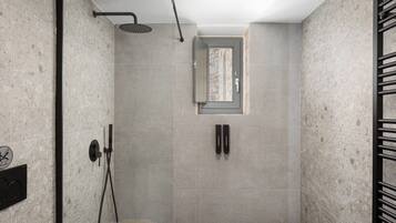A modern shower with a glass door, a towel rack, and a wall-mounted control panel.