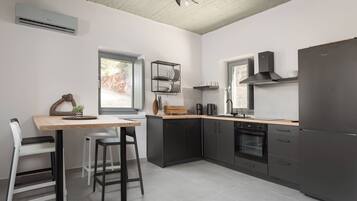 Una cocina moderna con una mesa de madera, taburetes de bar, horno empotrado y un refrigerador negro.