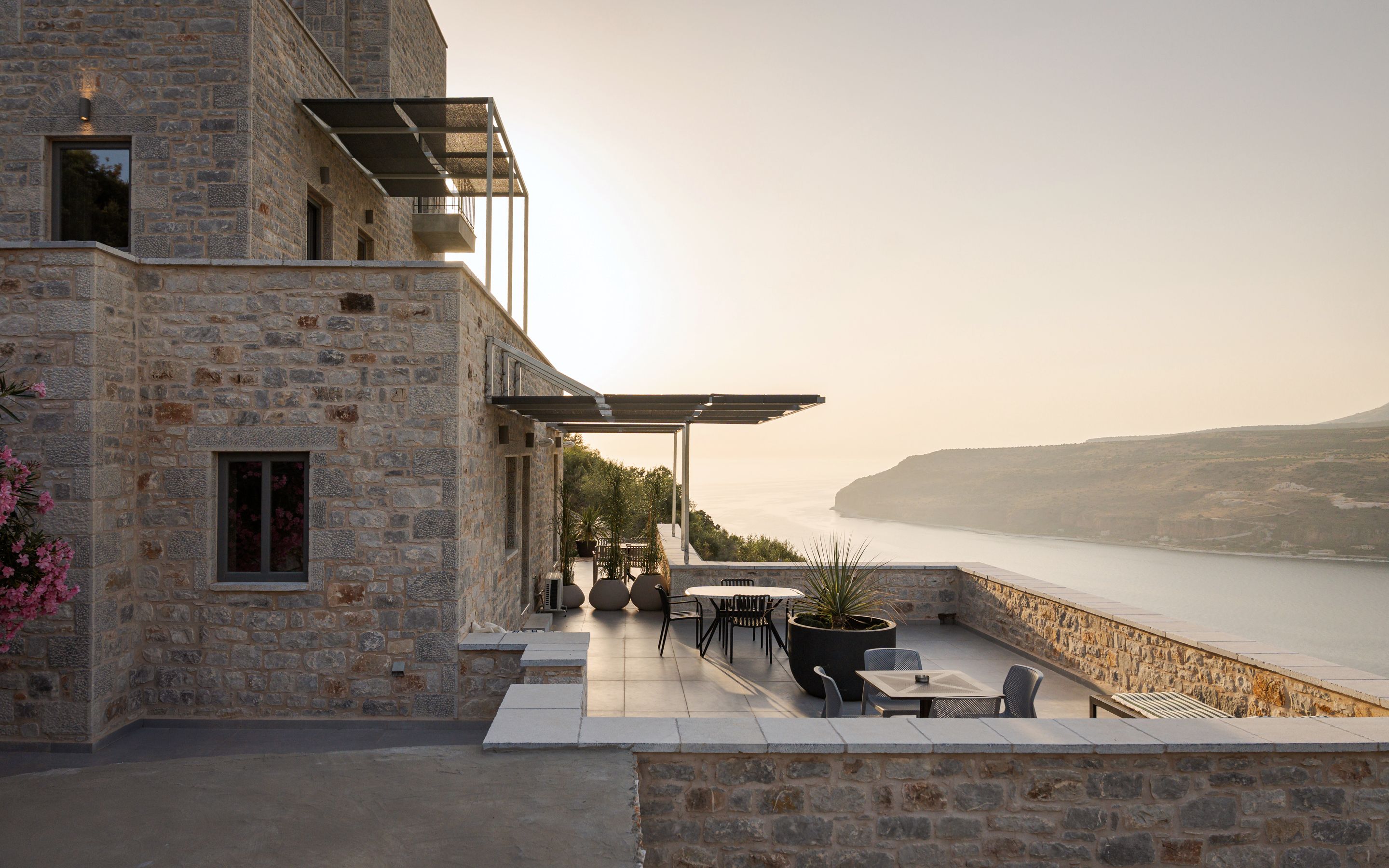 Un bâtiment en pierre doté d’une terrasse extérieure donnant sur un plan d’eau.