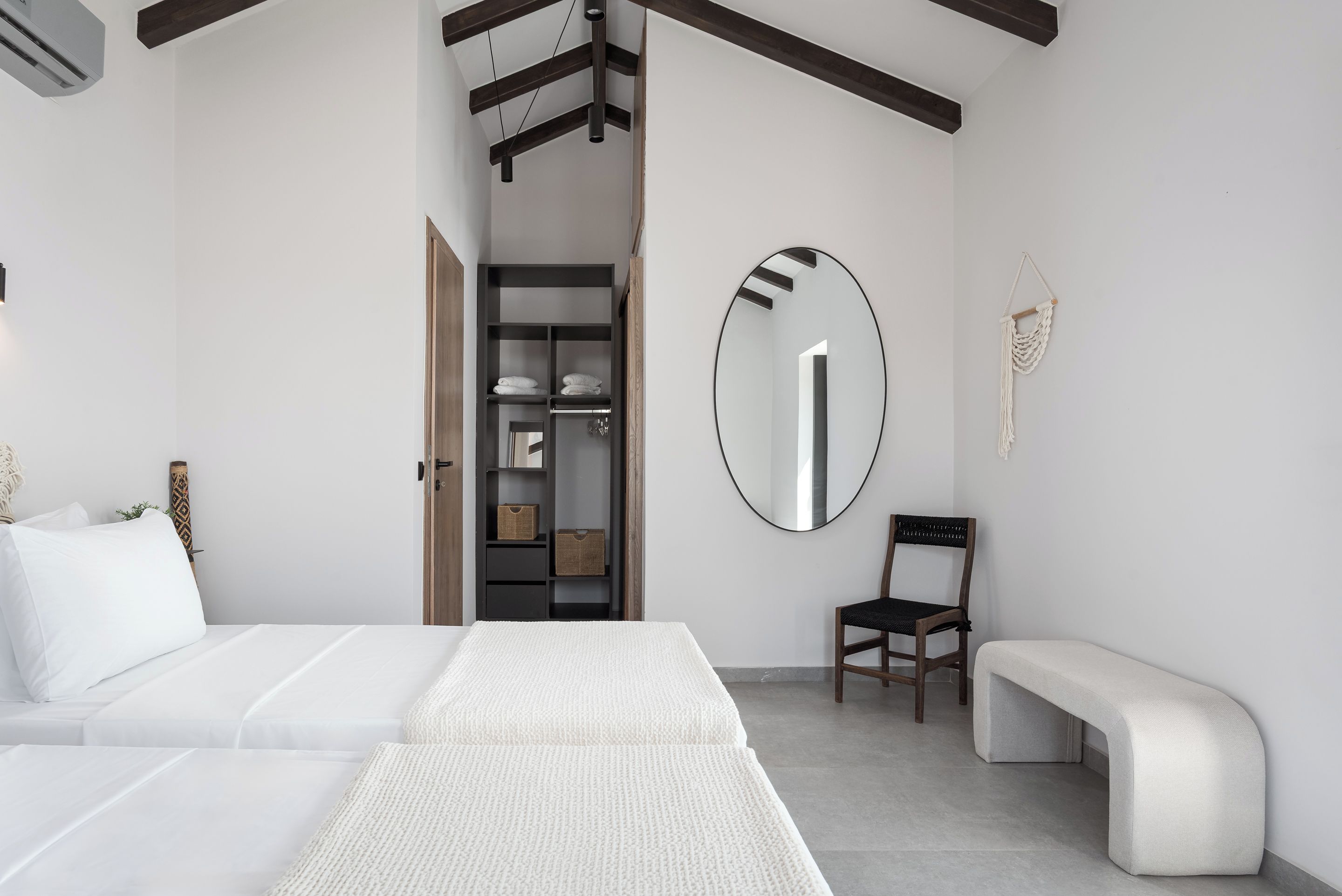 Une chambre à coucher moderne avec un grand lit, une chaise, un banc, une armoire et un miroir.