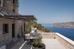 A stone building with a patio, outdoor furniture, and a view of the sea.