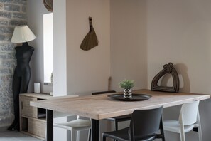 Un coin repas avec une table en bois, des chaises noires et blanches, une lampe noire et une plante décorative posée sur la table.