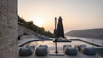 A poolside area with stone walls, seating, and a view of the water.