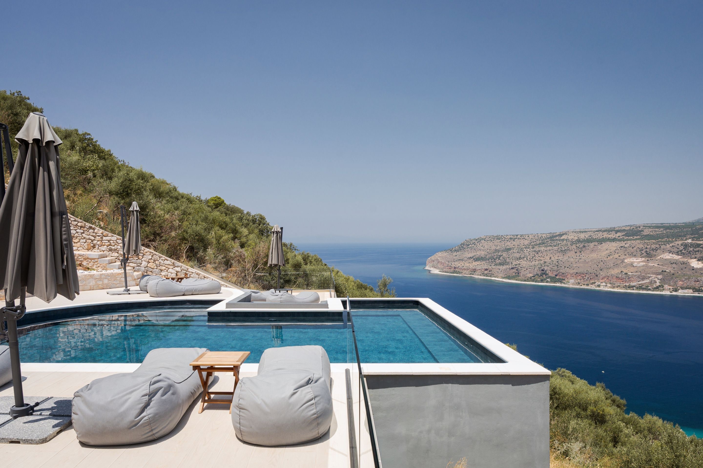 Una piscina infinita moderna con vista al mar y un paisaje montañoso.