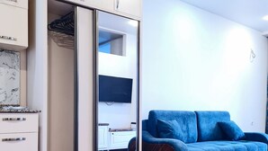 Ein Zimmer mit Kleiderschrank, blauem Sofa und Holzboden.