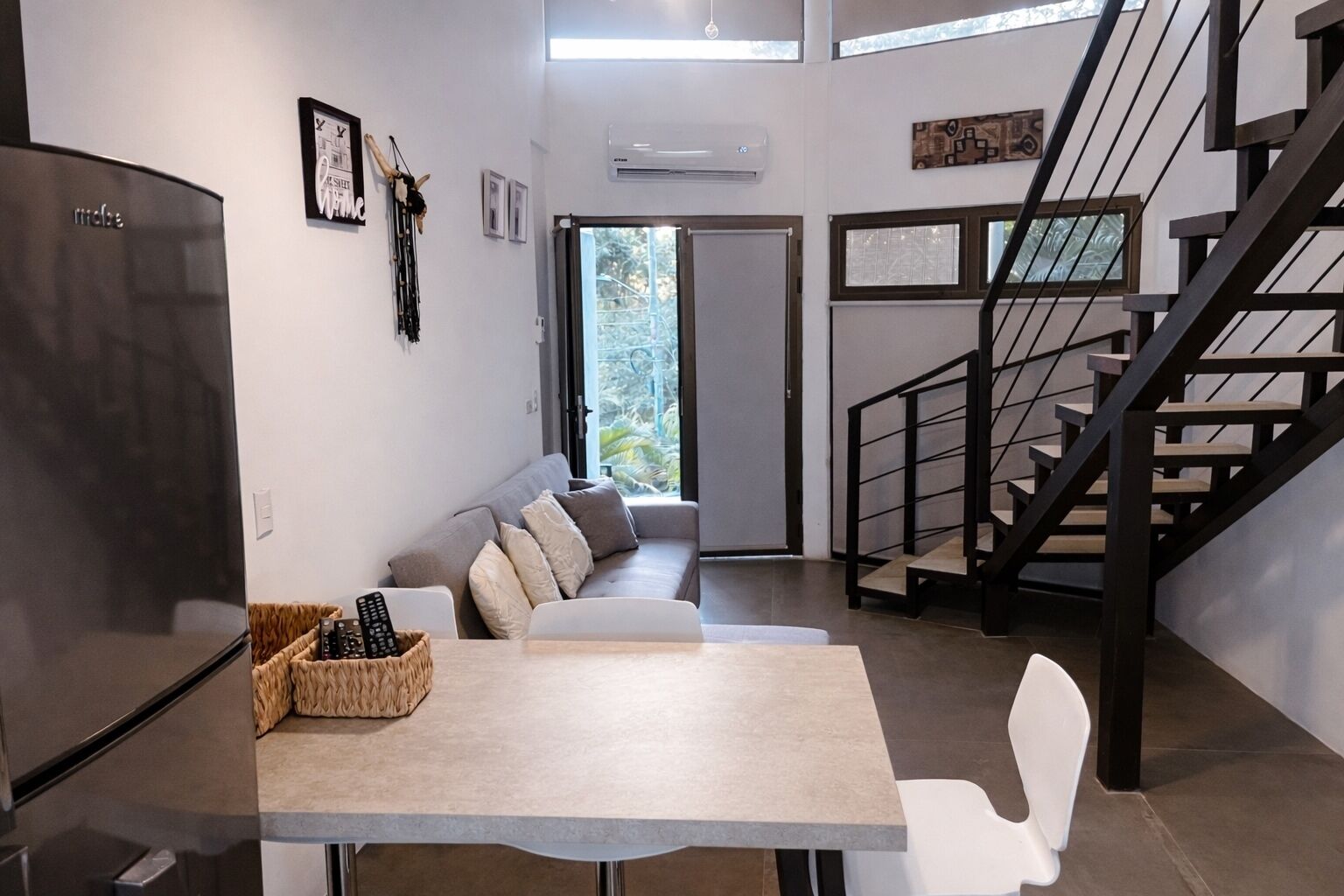 Una sala moderna con sofá, una mesa de comedor y una escalera.