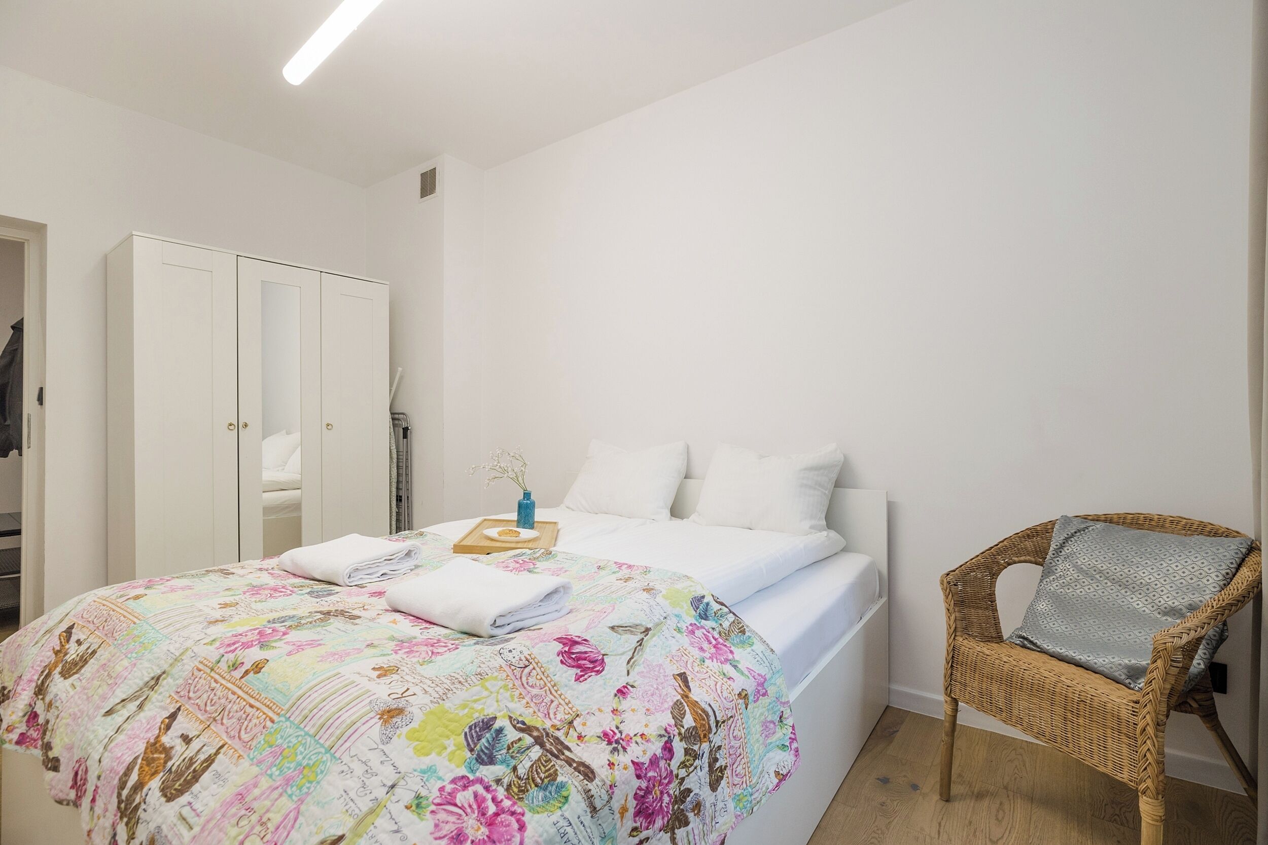 Un dormitorio con cama, una silla y un armario.