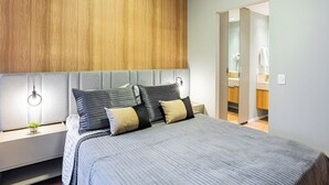 A modern bedroom with a large bed, a wooden headboard, bedside lamps, and a view into the bathroom. - Staybridge - Sophisticated space in Itaim Bibi (Itaim Bibi São Paulo)