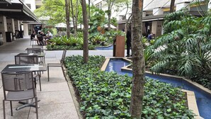 An outdoor seating area with tables and chairs, surrounded by greenery and a small pool. - Staybridge - Sophisticated space in Itaim Bibi (Itaim Bibi São Paulo)